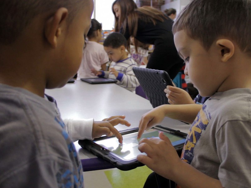 Two preschoolers playing on the same iPad.