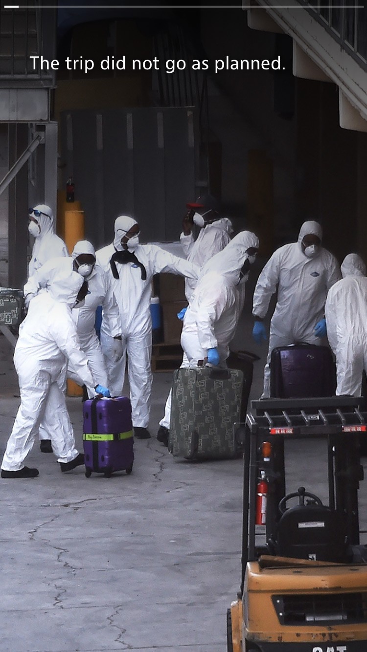 Several people in hazmat suits moving luggage.
