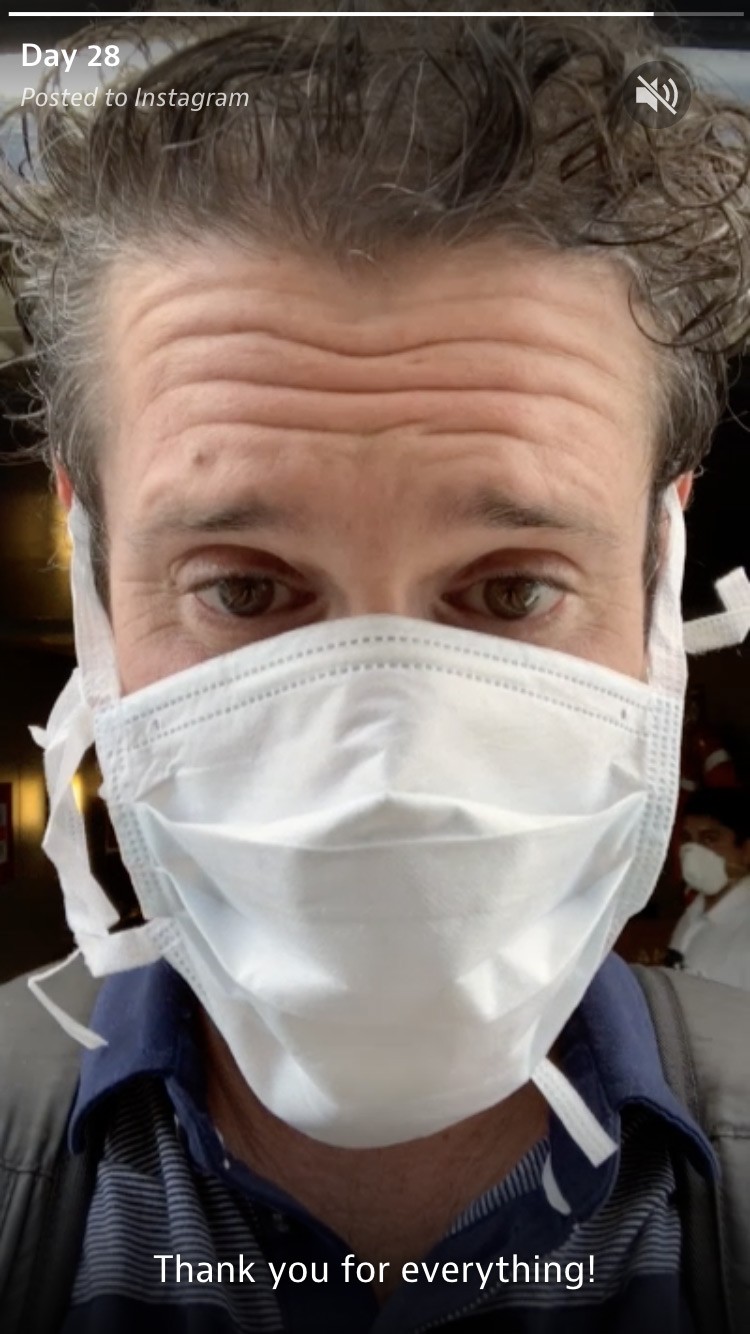 A still from a video of Brendt talking to camera with a surgical mask on.